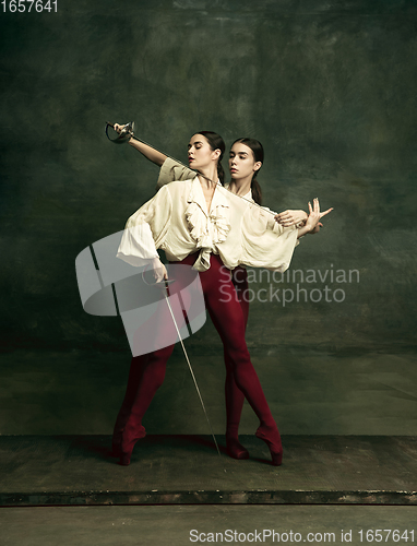 Image of Two young female ballet dancers like duelists with swords. Ballet and contemporary choreography concept. Creative art photo.