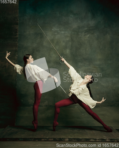 Image of Two young female ballet dancers like duelists with swords. Ballet and contemporary choreography concept. Creative art photo.