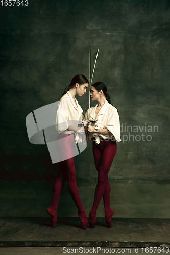 Image of Two young female ballet dancers like duelists with swords. Ballet and contemporary choreography concept. Creative art photo.