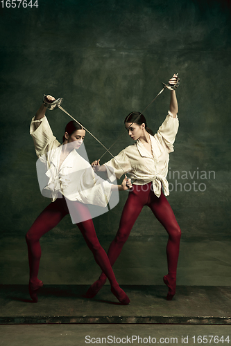 Image of Two young female ballet dancers like duelists with swords. Ballet and contemporary choreography concept. Creative art photo.