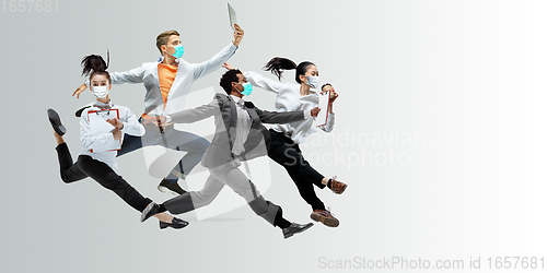 Image of Happy office workers in face masks jumping and dancing in casual clothes or suit isolated on studio background. Creative collage.