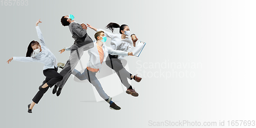 Image of Happy office workers in face masks jumping and dancing in casual clothes or suit isolated on studio background. Creative collage.