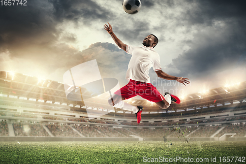 Image of Young man football player kicking ball during match at stadium. Flyer for ad, design.