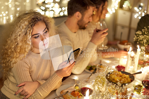 Image of woman with smartphone at dinner party with friends