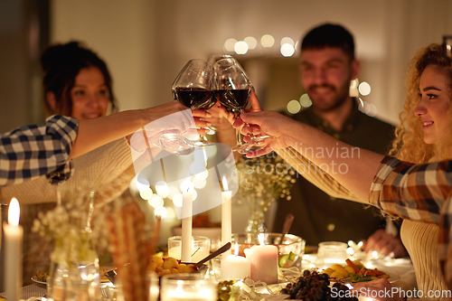 Image of happy friends drinking red wine at christmas party