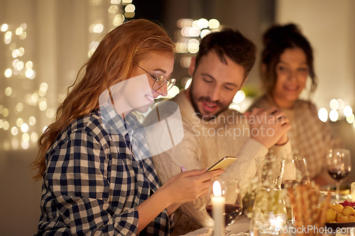 Image of friends with cellphone having dinner party at home