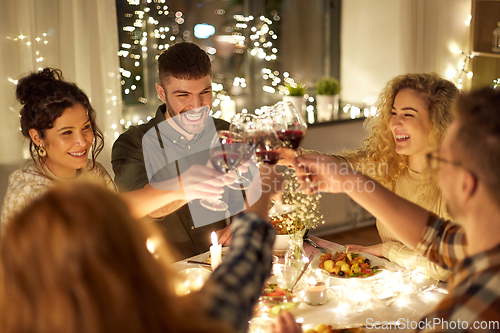 Image of happy friends drinking red wine at christmas party