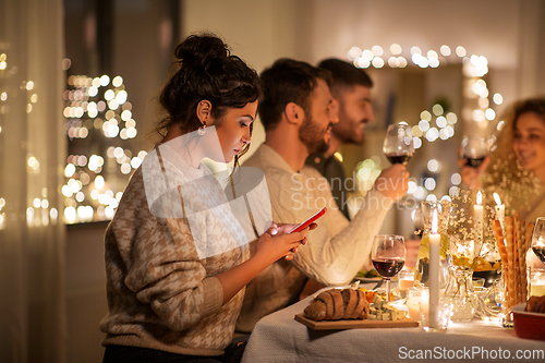 Image of woman with smartphone at dinner party with friends