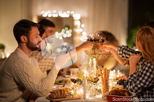 Image of man with smartphone at dinner party with friends