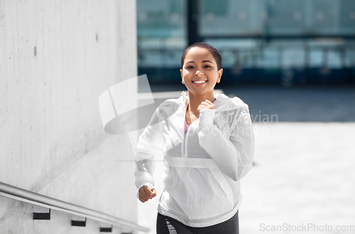 Image of african american woman running upstairs outdoors