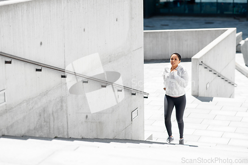 Image of african american woman running upstairs outdoors