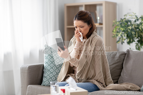 Image of sick asian woman with smartphone at home