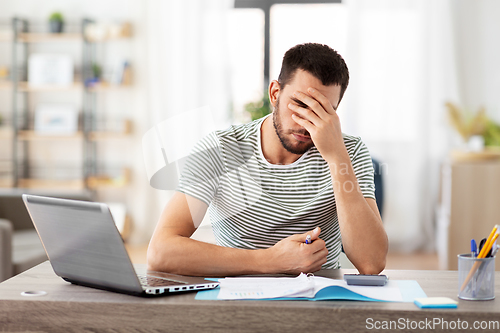 Image of man with files and calculator works at home office