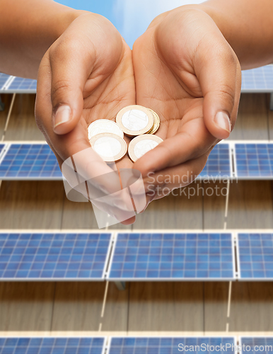 Image of hands holding money over solar panels