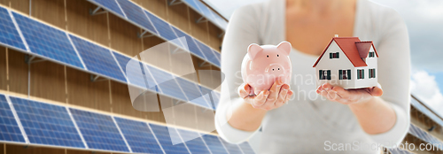 Image of woman with house and piggy bank over solar panels