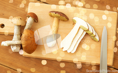 Image of edible mushrooms, kitchen knife and cutting board