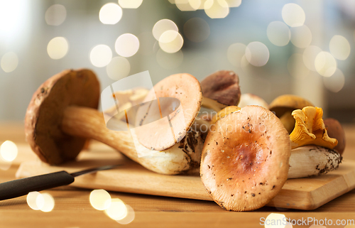 Image of edible mushrooms on wooden cutting board and knife