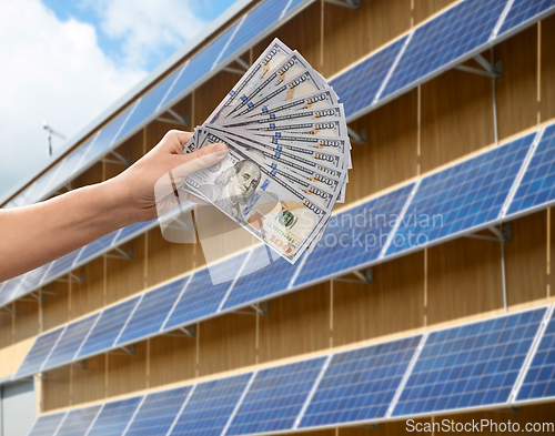 Image of hands holding money over solar panels