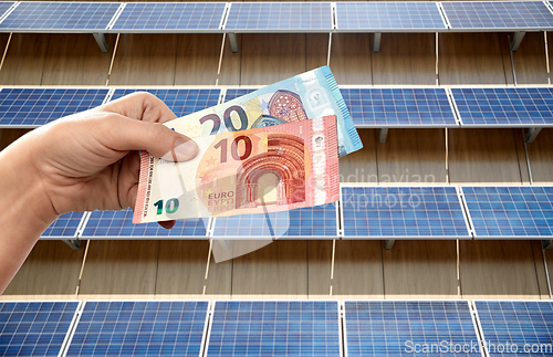 Image of hands holding money over solar panels