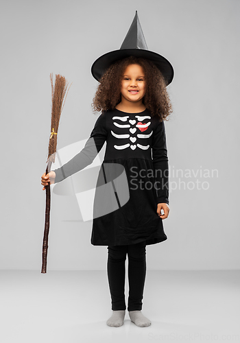 Image of girl in black witch hat with broom on halloween