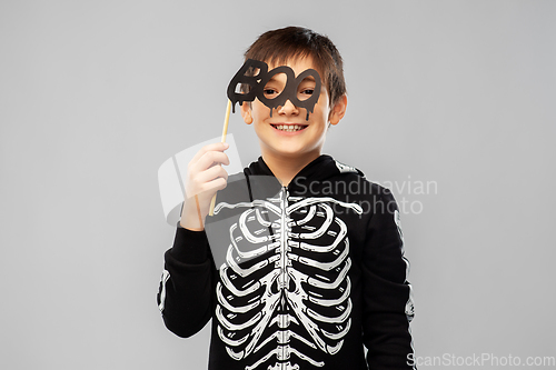Image of boy in halloween costume of skeleton with props
