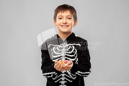 Image of boy in halloween costume of skeleton with candies