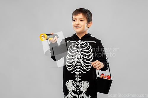 Image of boy in halloween costume with candies and torch