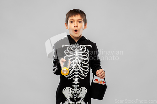 Image of boy in halloween costume with candies and torch