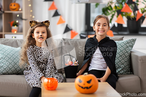 Image of girls in halloween costumes with candies at home