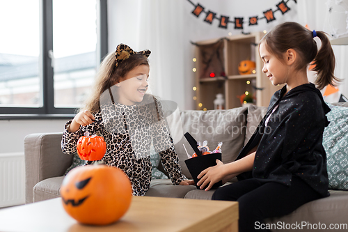 Image of girls in halloween costumes with candies at home