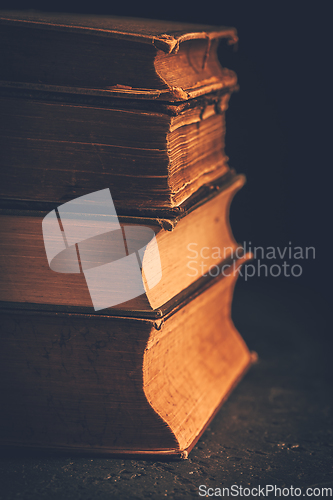 Image of Stack of antique leather bound books against dark background