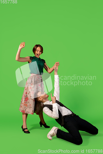 Image of Old-school fashioned young woman dancing isolated on green background