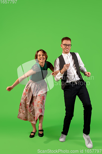 Image of Old-school fashioned young woman dancing isolated on green background