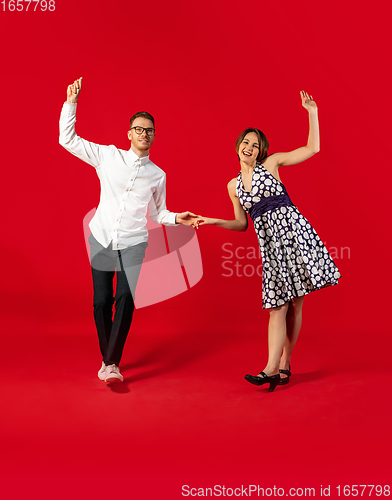 Image of Old-school fashioned young couple dancing isolated on red background