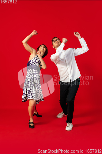 Image of Old-school fashioned young couple dancing isolated on red background