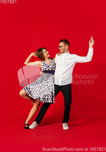 Image of Old-school fashioned young couple dancing isolated on red background