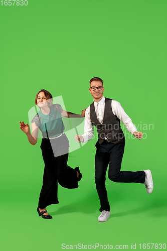 Image of Old-school fashioned young woman dancing isolated on green background