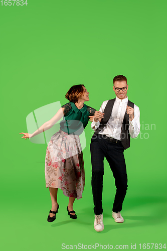 Image of Old-school fashioned young woman dancing isolated on green background