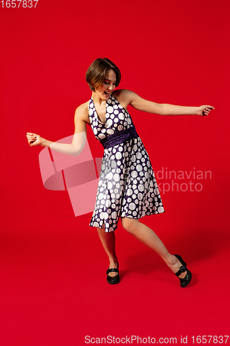 Image of Old-school fashioned young woman dancing isolated on red background