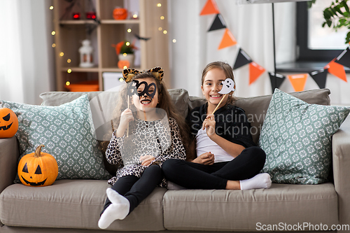 Image of girls in halloween costumes with pumpkins at home