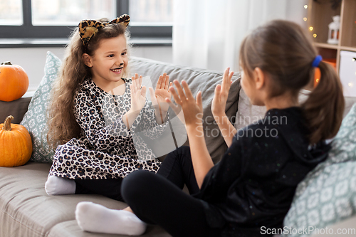 Image of girls in halloween costumes playing game at home