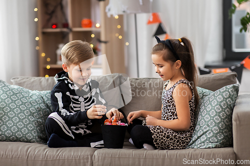 Image of kids in halloween costumes with candies at home