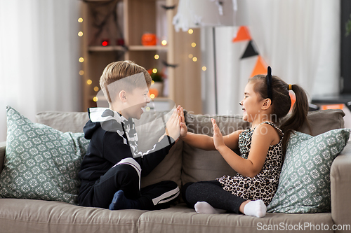 Image of kids in halloween costumes playing game at home