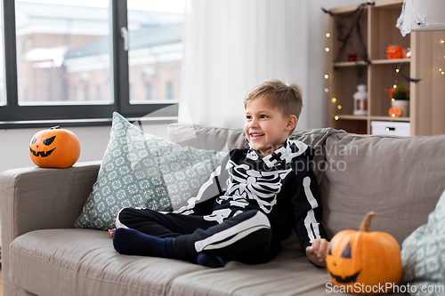 Image of happy boy in halloween costume of skeleton at home