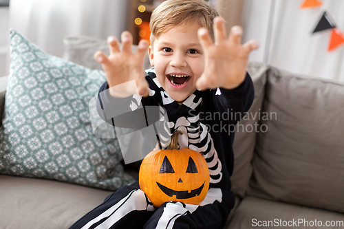 Image of happy boy in halloween costume of skeleton at home