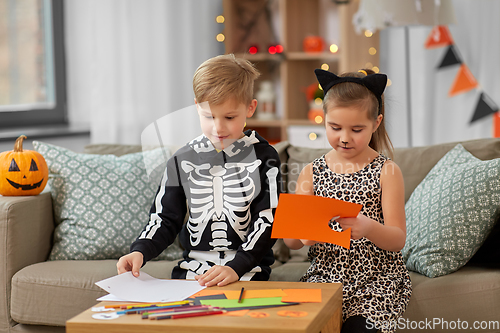 Image of kids in halloween costumes doing crafts at home