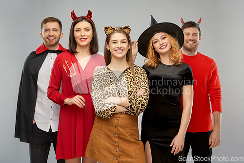 Image of happy friends in halloween costumes over grey
