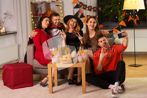 Image of happy friends in halloween costumes taking selfie