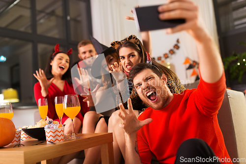 Image of happy friends in halloween costumes taking selfie
