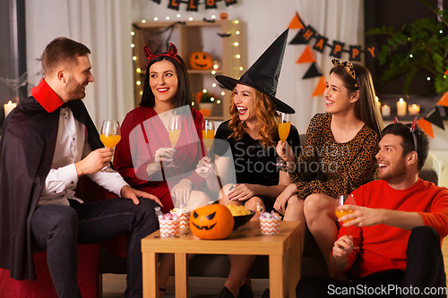 Image of happy friends in halloween costumes at home party